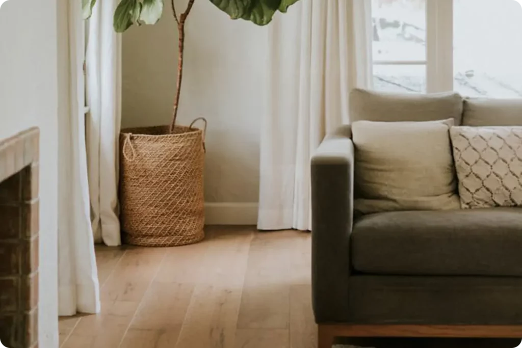 Aufgeräumtes Wohnzimmer mit einem Sofa, einem Kamin sowie einer Zimmerpflanze