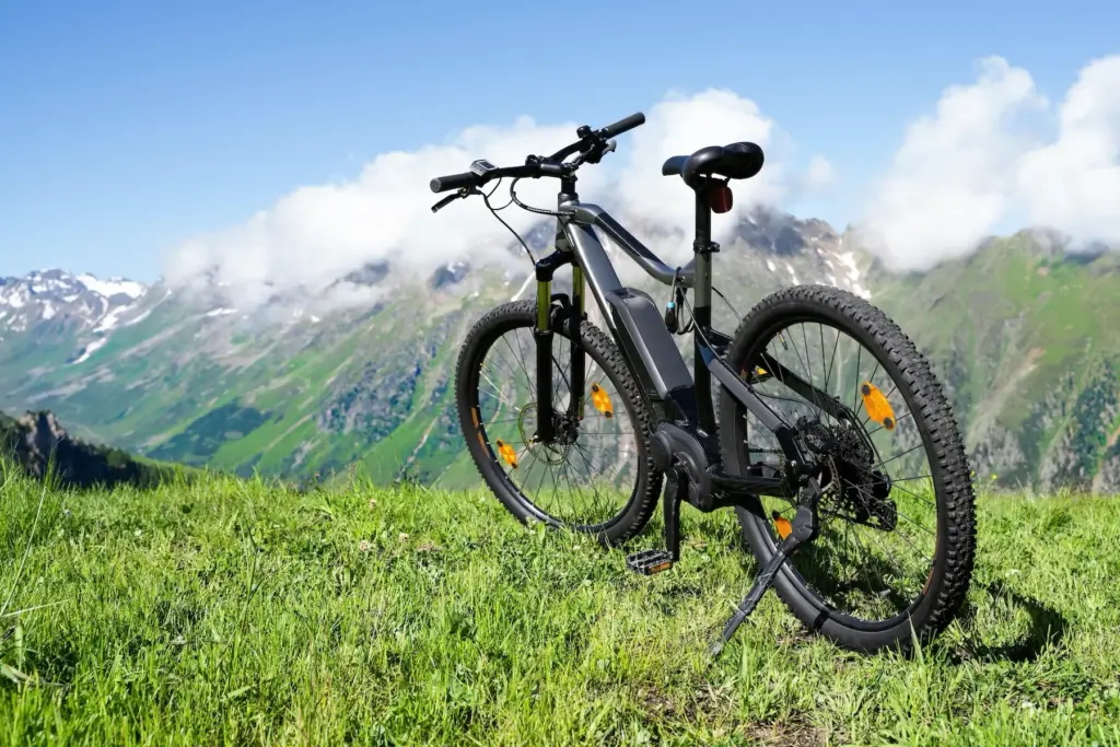 Freistehendes E-Bike bei einer Fahrradtour vor einer sonnigen Aussicht mit Bergen.
